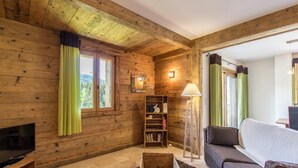 Un interior de madera con televisor, estantería, sofá y lámpara.