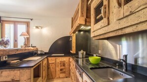 Una cocina con armarios de madera, encimera negra, pileta de acero inoxidable y un tazón verde.