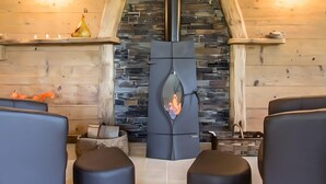 Un interior moderno con chimenea de piedra, paredes de madera y asientos negros.