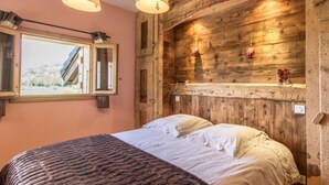 Un dormitorio con cabecera de madera, un ventanal grande y una cama con ropa de cama blanca.