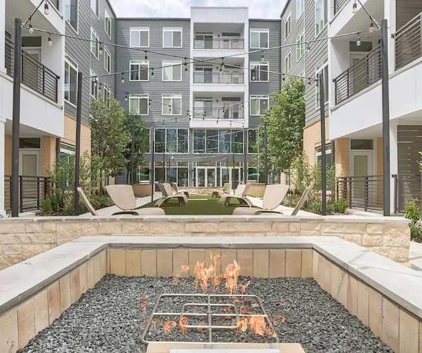 Relax by the central fire pit in this serene courtyard, surrounded by lush greenery and comfortable lounge chairs.