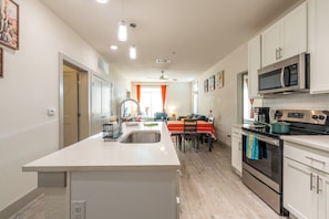 Enjoy cooking in this well-lit kitchen with a central island, sink, stove, and microwave.