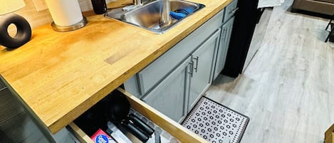 A modern kitchen with a wooden countertop, stainless steel sink, and a built-in oven.