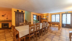 Comedor con una larga mesa, sillas, chimenea y una puerta que indica 'SALIDA'.