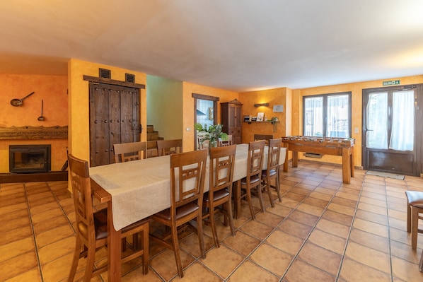 A dining area with a long table, chairs, a fireplace, and a door marked 'SALIDA'.
