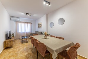 Zona pranzo con tavolo, sedie, televisore e divano.