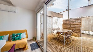 A modern living room with a sofa, a glass door leading to an outdoor patio with a table and chairs. - Nice home in Royan with WiFi (Royan)