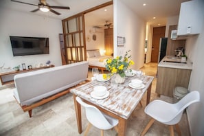 Cozy living area with a dining table for two, flat-screen TV, and a large window.