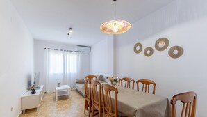 A dining area with a table, chairs, a hanging light fixture, and wall decorations.