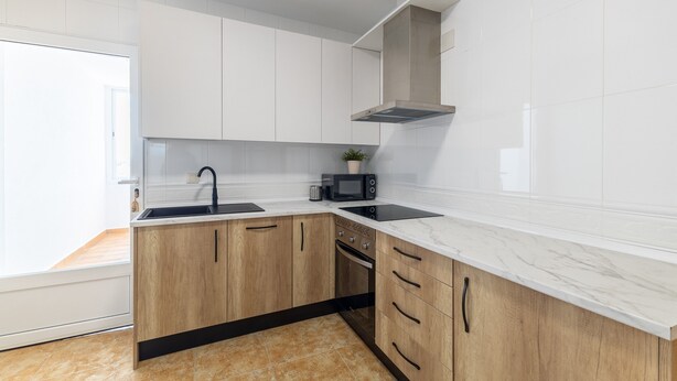 A modern kitchen with white cabinets, a black countertop, and a microwave.