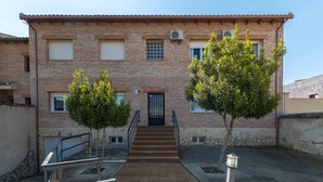 A two-story brick building with a central staircase, a door at the ground level, and two trees in the courtyard.