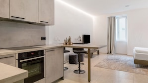 A modern kitchen with a built-in oven and a dining area with stools.