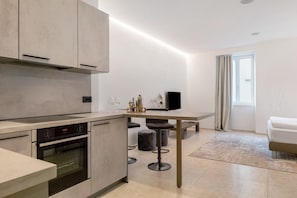 A modern kitchen with a built-in oven and a dining area with stools.