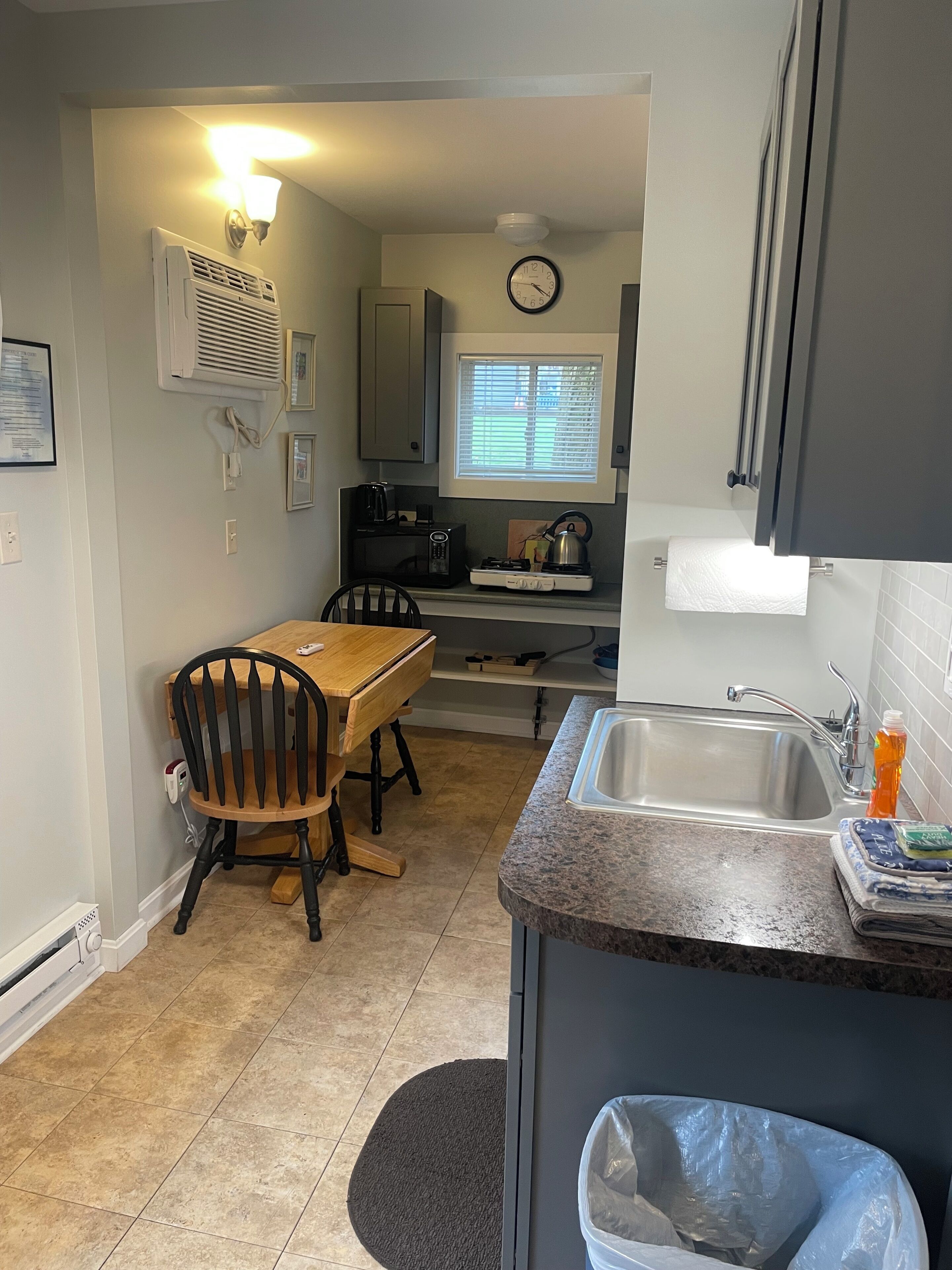A compact kitchen with a dining table, chairs, a sink, and a stove.