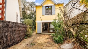 A yellow house with a brick wall, a paved pathway, and a garden area.