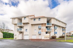 A multi-story residential building with balconies, a parking area, and a gated entrance. - The Marin’s Cabin, pool, sleeps 4 (Pornic)