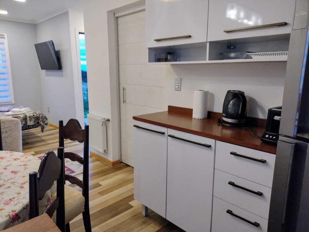 Una cocina compacta con armarios blancos, encimera de madera y cafetera integrada.