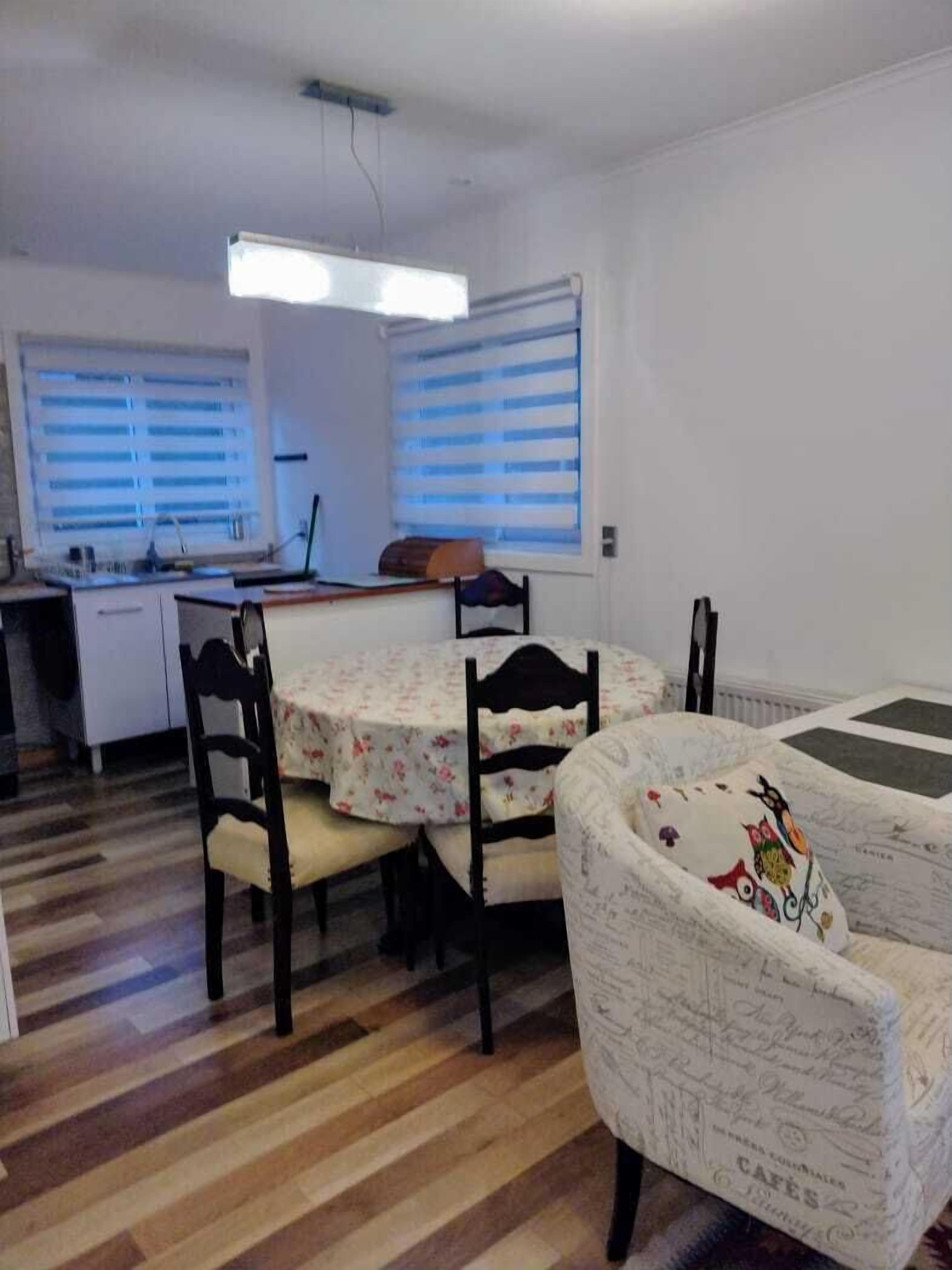 A dining area with a round table, two chairs, and a patterned sofa.