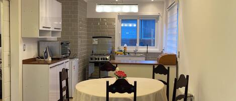 Un espacio habitable compacto con comedor, kitchenette y sofá.