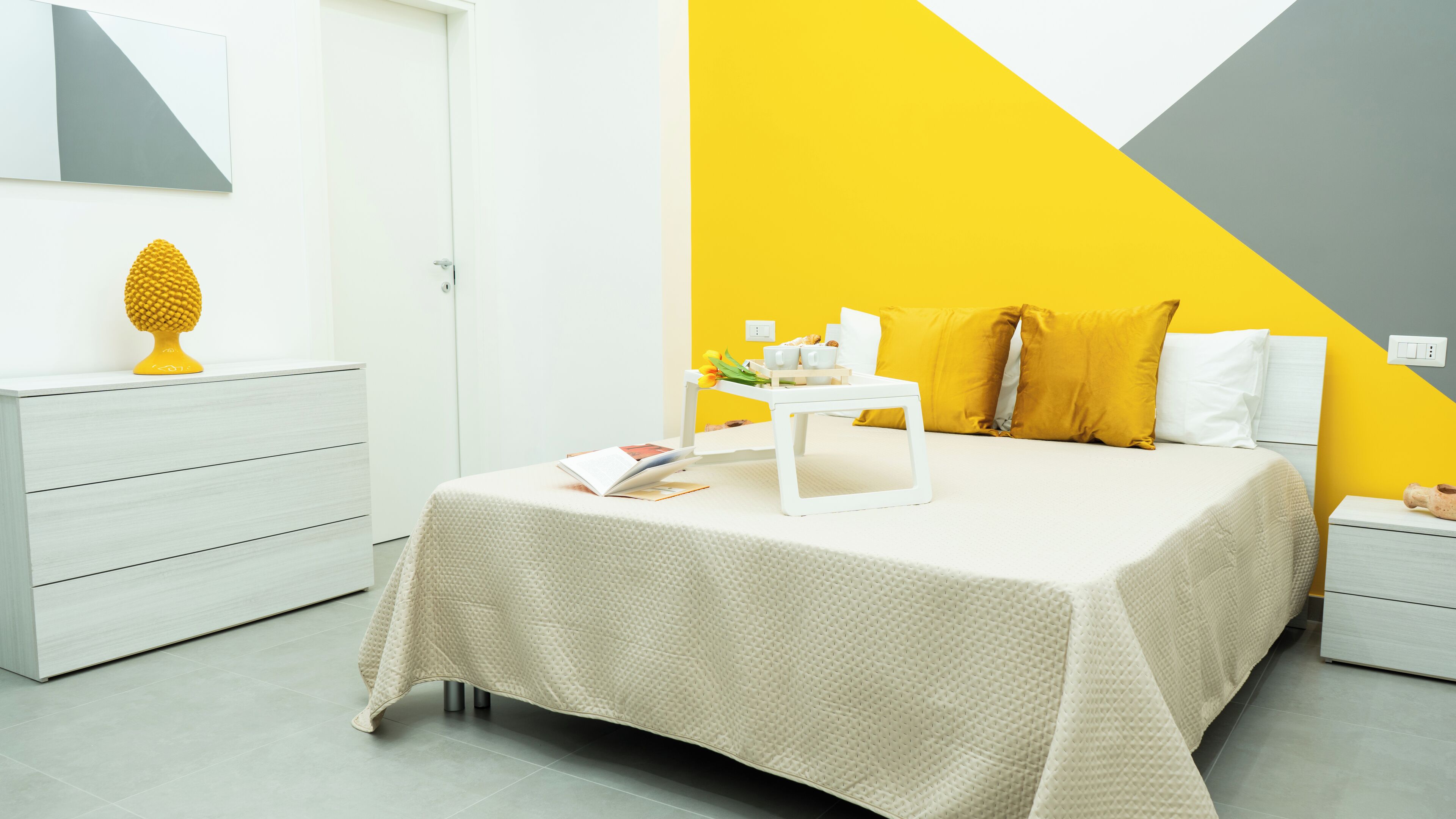 Ein modernes Schlafzimmer mit einem Bett, Nachttischen und einem Nachttisch mit Lampe.