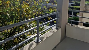A balcony with a metal railing, a view of greenery, and a clear sky. - Between Green and Ocean, with Private Terrace - 123 (Pornic)