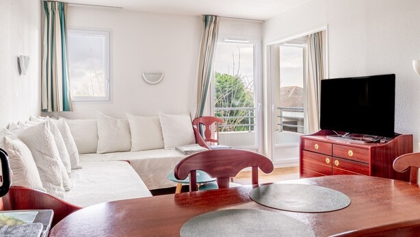 A hotel room with a bed, a TV, a dining table, and a view of the outdoors. - Between Green and Ocean, with Private Terrace - 123 (Pornic)