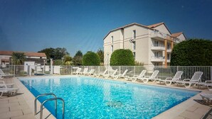 A rectangular swimming pool with clear blue water, surrounded by white lounge chairs and a white fence. - Between Green and Ocean, with Private Terrace - 123 (Pornic)