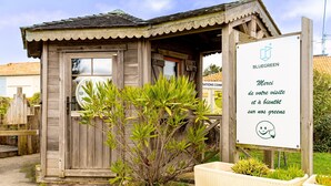 A wooden building with a door, a sign with text, and a plant in front. - Between Green and Ocean, with Private Terrace - 123 (Pornic)