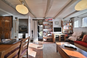 A cozy living room with a fireplace, wooden furniture, a bookshelf, and a television. - Chalet En so de Gusti – Peaceful Escape in the Pyrenees, Perfect for Hiking & Relaxation (Bonac-Irazein)
