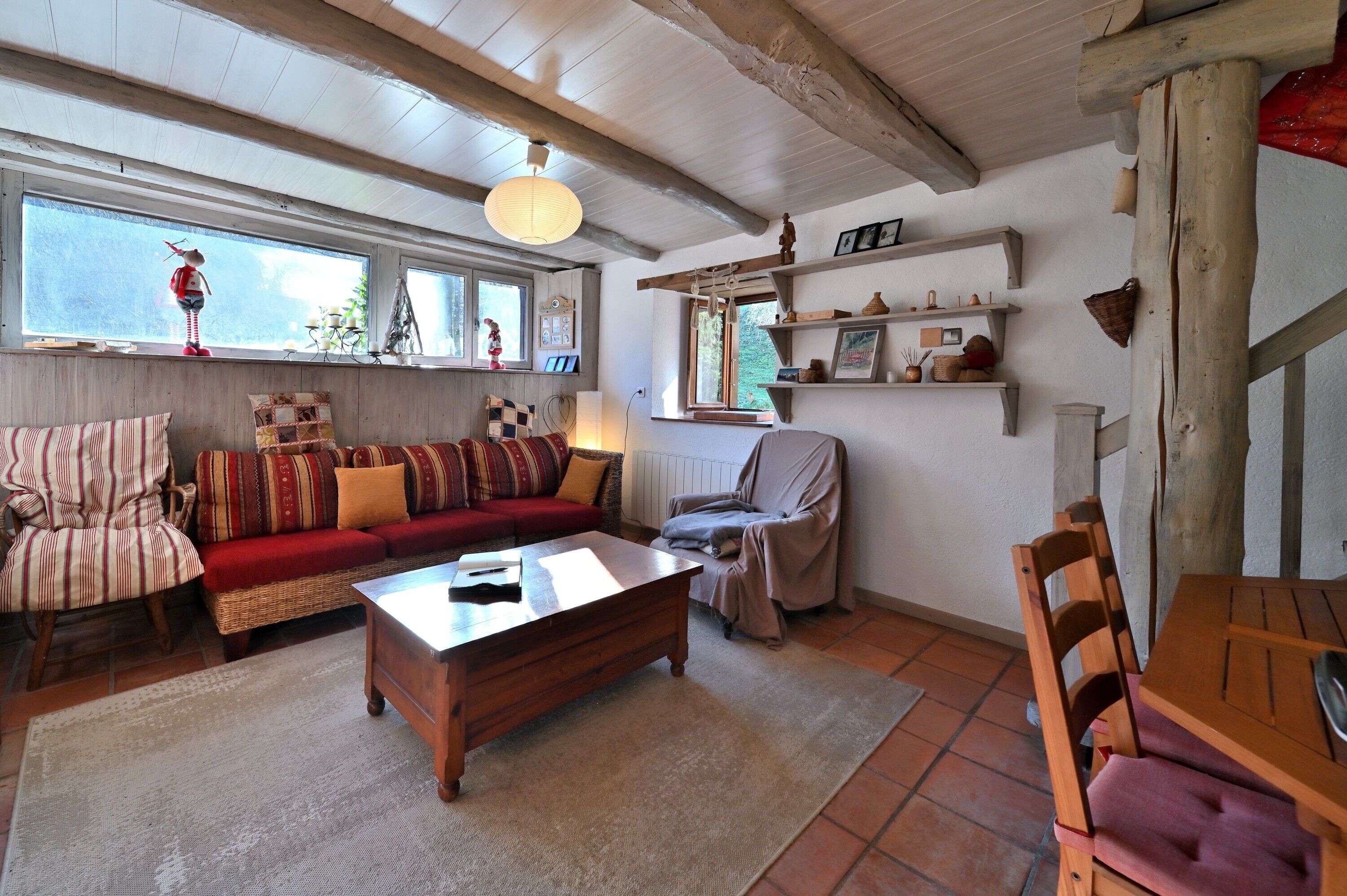 A cozy living room with a sofa, armchair, wooden coffee table, and a dining table.