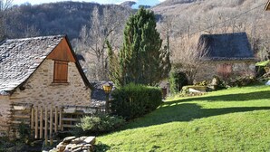 Una cabaña de piedra con techo inclinado, valla de madera y césped cuidado.