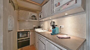 A compact kitchen with a built-in oven, a coffee machine, and a sink.