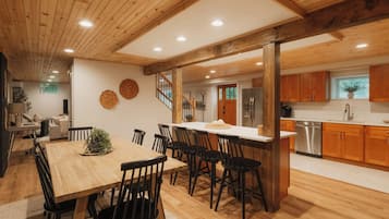 Una cocina amplia con armarios de madera, un refrigerador de acero inoxidable y un comedor con mesa y sillas de madera.