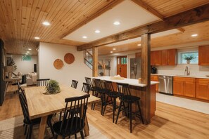 A spacious kitchen with wooden cabinets, a stainless steel refrigerator, and a dining area with a wooden table and chairs.