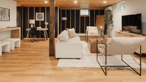 Una sala de estar moderna con techo de madera, un sofá, una mesa de centro y un televisor.