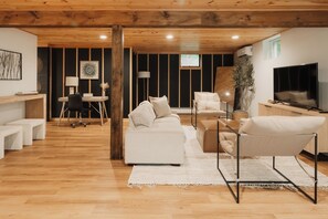 Un soggiorno moderno con soffitto in legno, un divano, un tavolino da caffè e una TV.