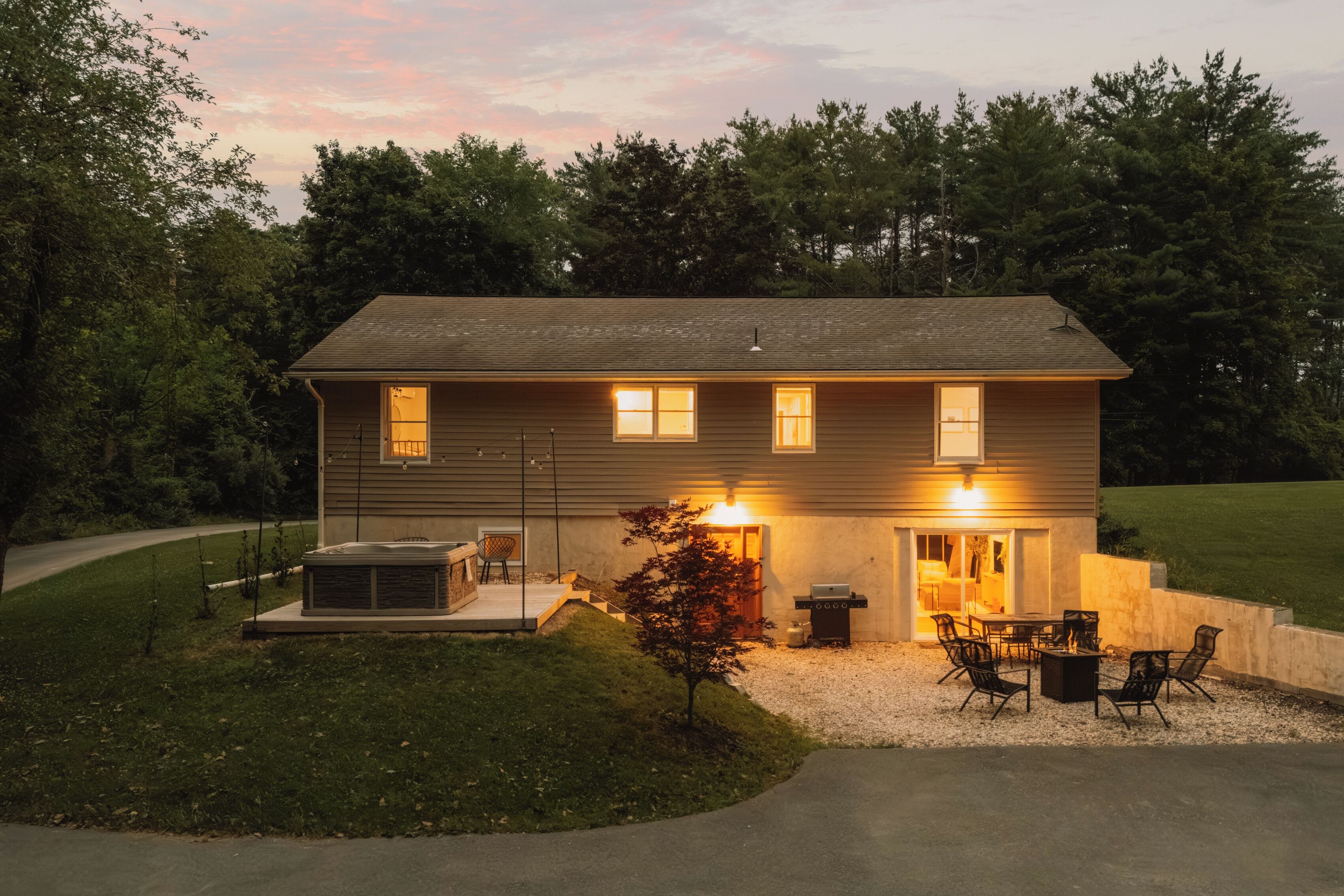 A two-story house with a patio area, outdoor seating, and a hot tub.
