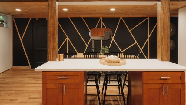 Una cocina moderna con una isla central, armarios de madera y un revestimiento mural de estampado geométrico.