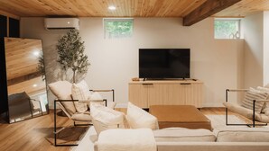 Una sala de estar moderna con un televisor de pantalla plana, techo de madera y un gran ventanal.