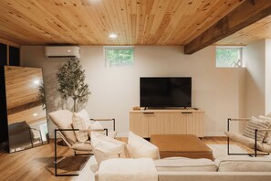 Un soggiorno moderno con televisore a schermo piatto, soffitto in legno e un'ampia finestra.