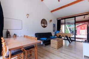 A room with a wooden dining table, black sofa, and a foosball table. - Holiday Home 'Home Sweet Home Moliets' with Shared Pool, Private Terrace & Wi-Fi (Moliets-et-Maa)
