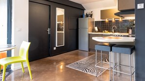 Een moderne keuken met een zwarte deur, een koelkast, een spoelbak en twee barstoelen.