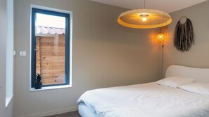Een slaapkamer met een bed, een raam, een wandlamp en een decoratie aan de muur.