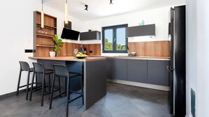 A modern kitchen with a central island, bar stools, a TV, and a large window. - Amazing home in Rovinj (Rovinj)