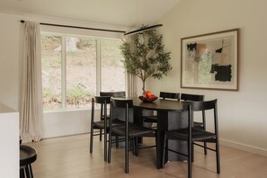 A dining area with a round table, black chairs, a potted plant, and a framed abstract painting on the wall. - Beaver Lodge at Carter Bridge Estate (Freehold)