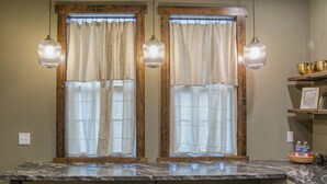 Un baño con dos ventanas, encimera de mármol y tres sillas.