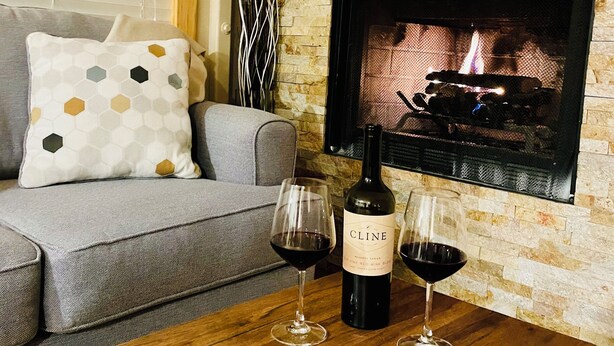 Un salon avec une cheminée, un canapé, une table basse et deux verres à vin.