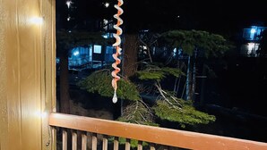 Un balcon avec une balustrade en bois, deux chaises en bois, une petite table ronde et deux verres à vin.