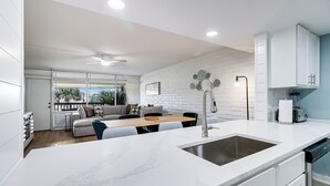 A modern kitchen with a marble countertop, integrated sink, and white cabinetry.