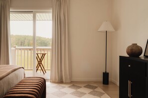 A bedroom with a bed, a nightstand, a lamp, a dresser, and a view of a balcony.